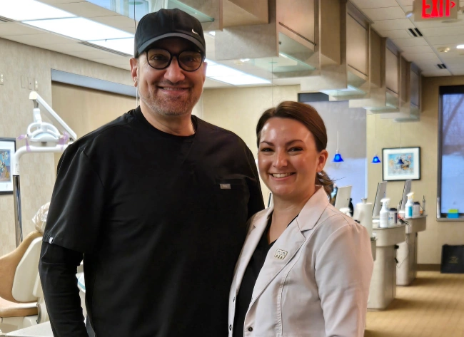 Two people smiling at camera in modern orthodontic office reception area.